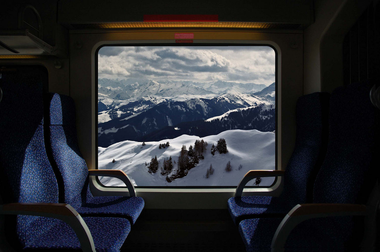 Window of Train and Snow Capped Mountains